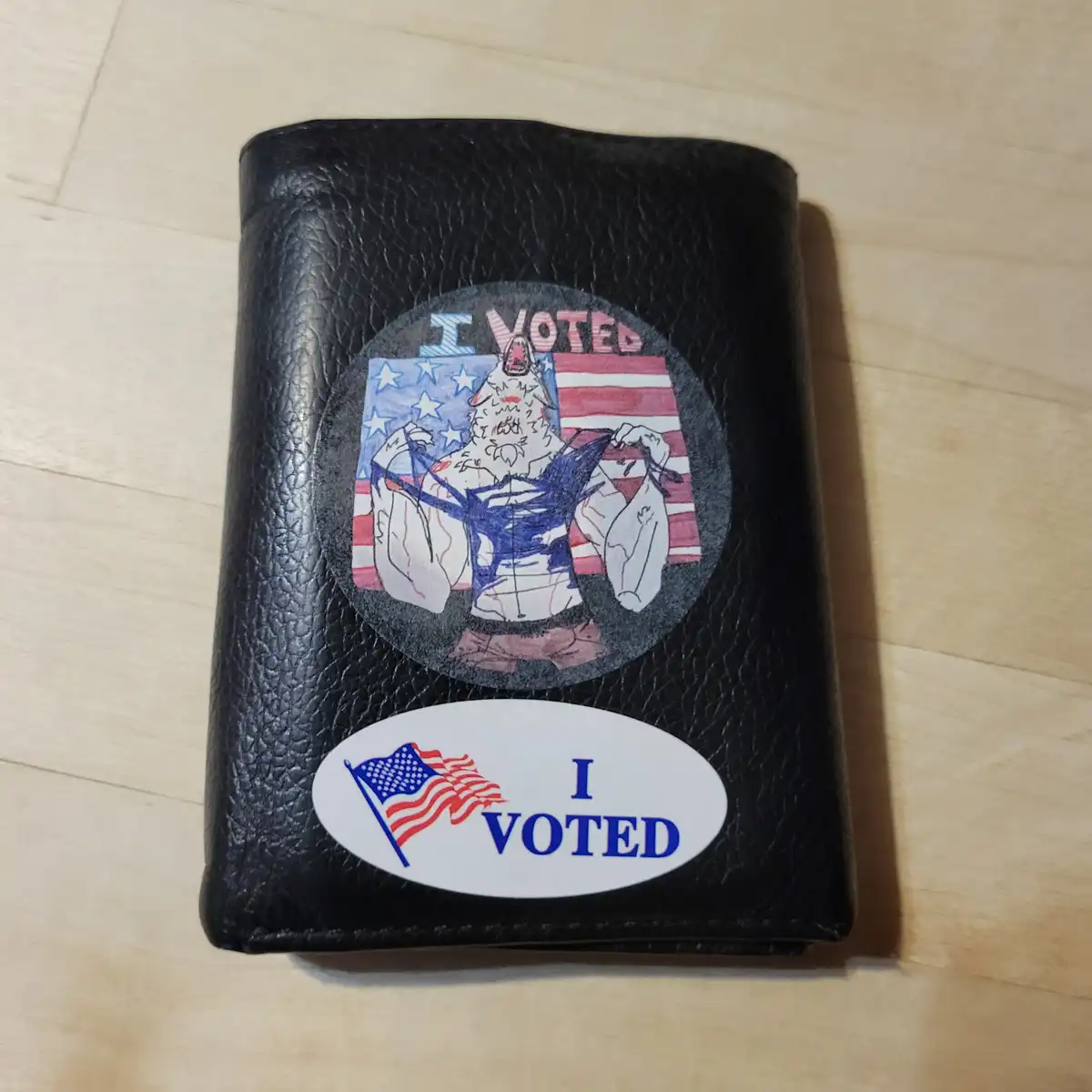 A black leather wallet rests on a wooden surface, adorned with two 'I VOTED' stickers. The top sticker features a…