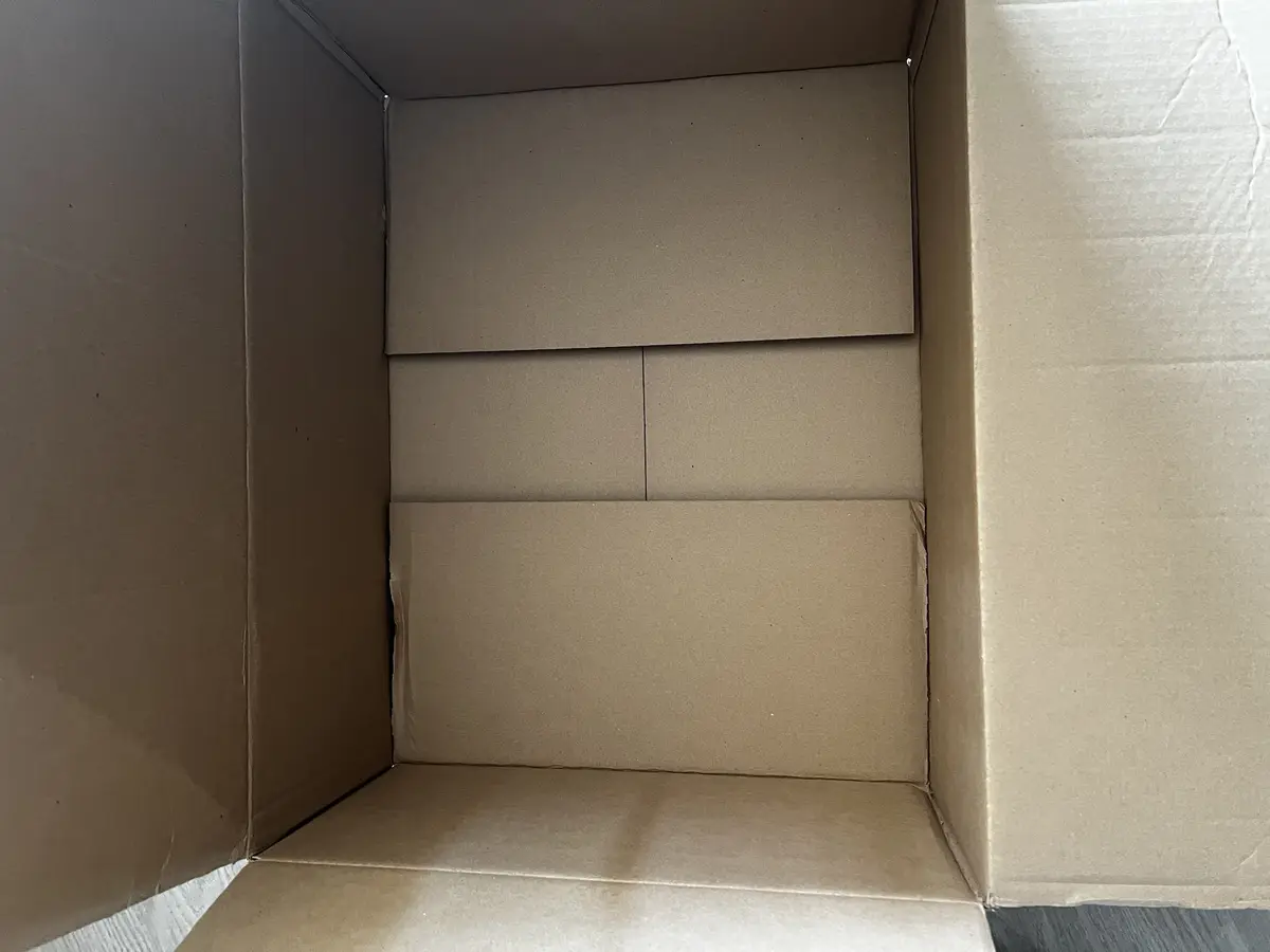 A top-down view of an empty brown cardboard box, showing its interior flaps and seams. The overlaid text reads 'this box is…