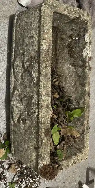 A weathered, rectangular concrete planter with decorative embossed patterns on its side lies on a concrete surface, filled…