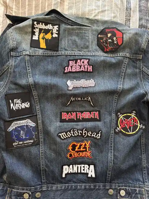 A denim jacket covered in patches from heavy metal bands including Black Sabbath, Metallica, Iron Maiden, Slayer, Motörhead…