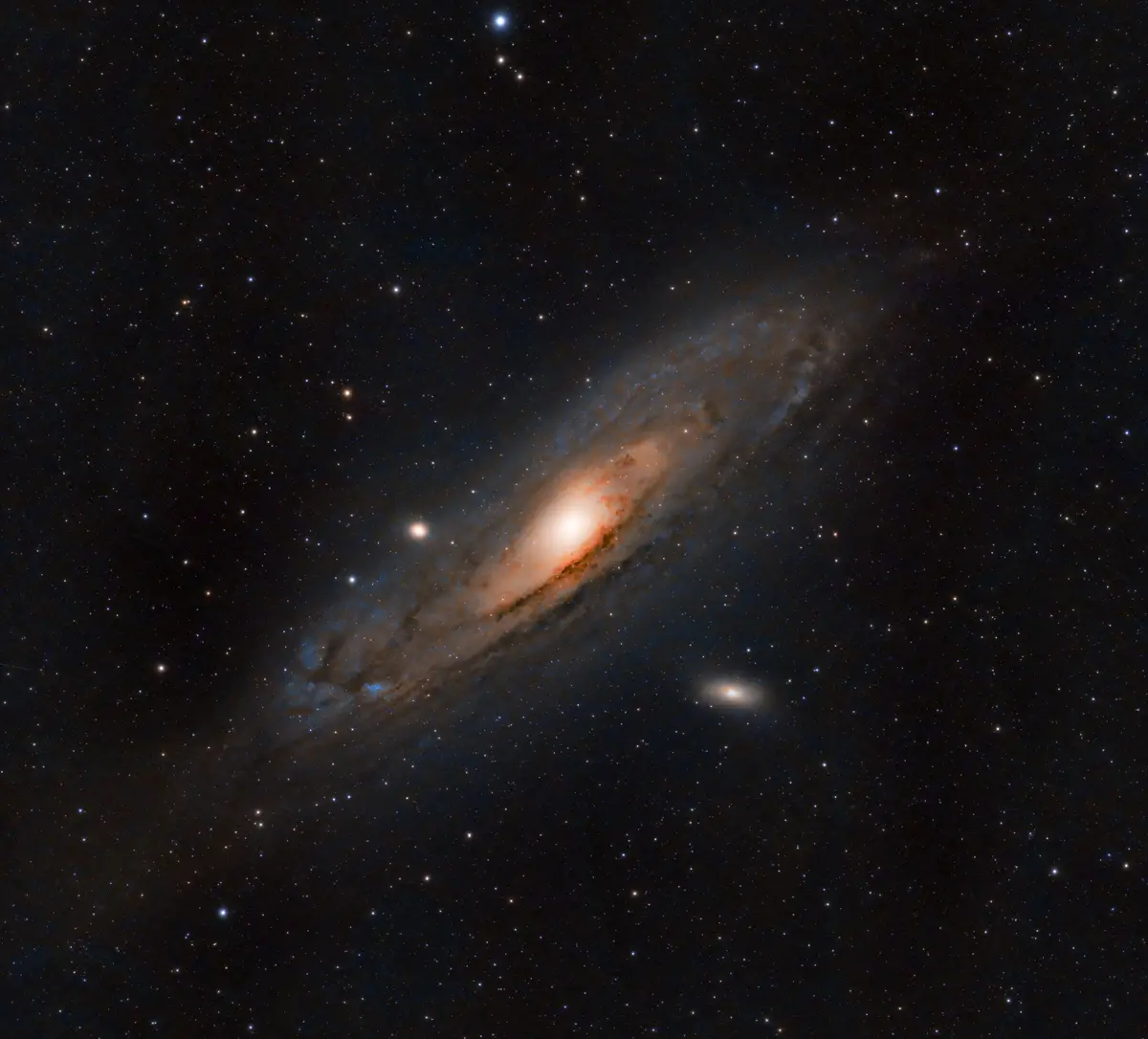A deep-space photograph shows a spiral galaxy with a bright central core and swirling arms of orange and blue gas and dust…