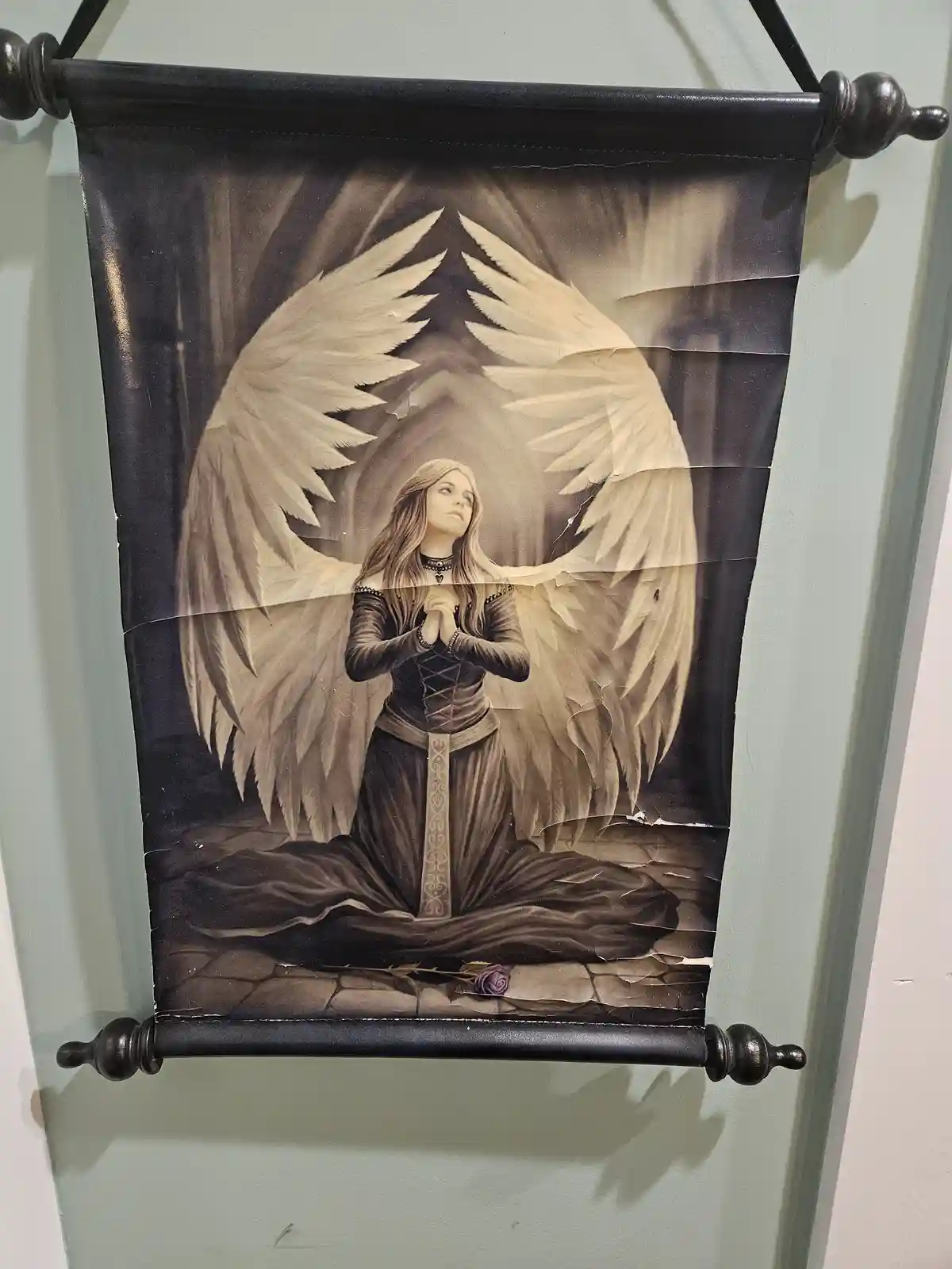 A torn, sepia-toned fantasy banner depicts a kneeling angel with large, feathered wings, hands clasped in prayer, and a…