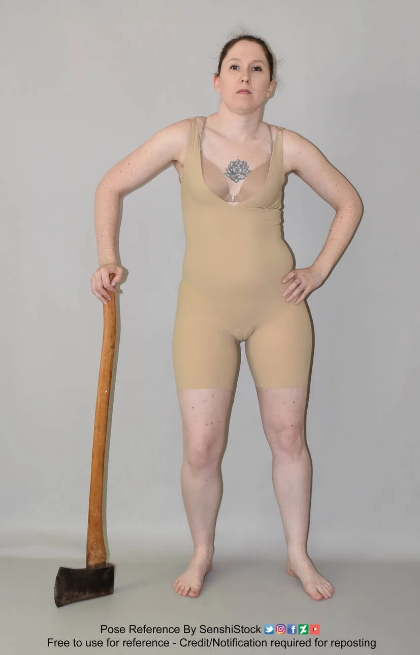 A woman stands confidently with hands on hips, holding an axe in one hand, wearing a beige bodysuit with a visible tattoo on…