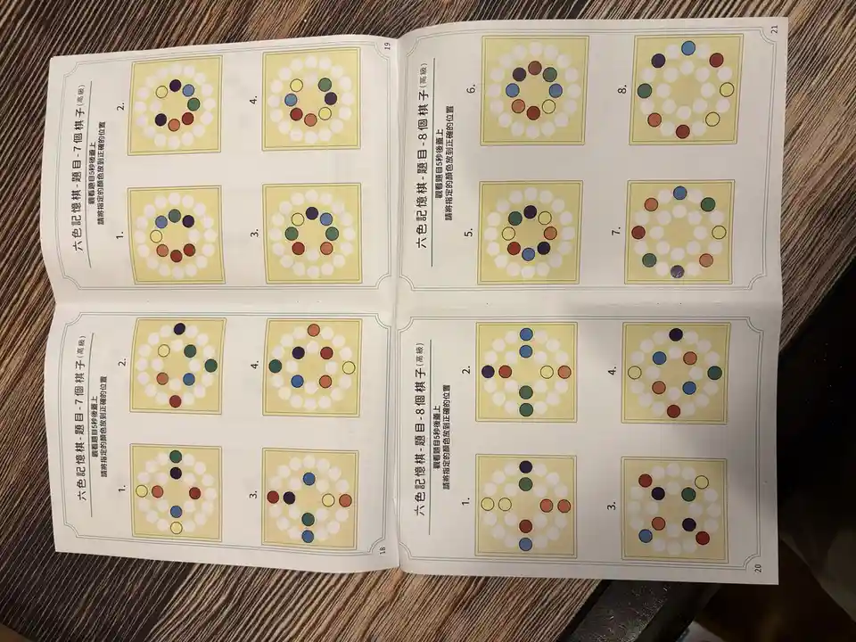 An open book displays pages with memory games featuring colorful circles arranged in patterns on a grid, labeled with…