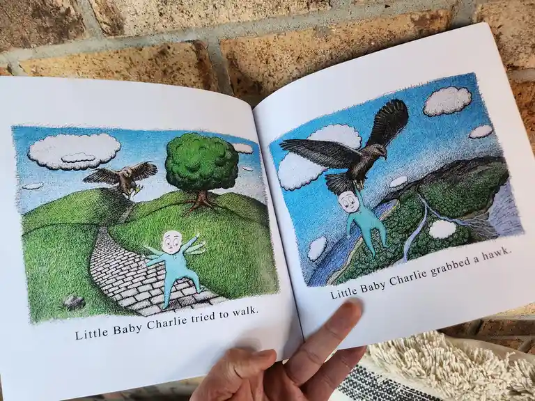 An open children's book shows two pages: left, a baby in blue pajamas attempts to walk on a path as a hawk flies nearby…