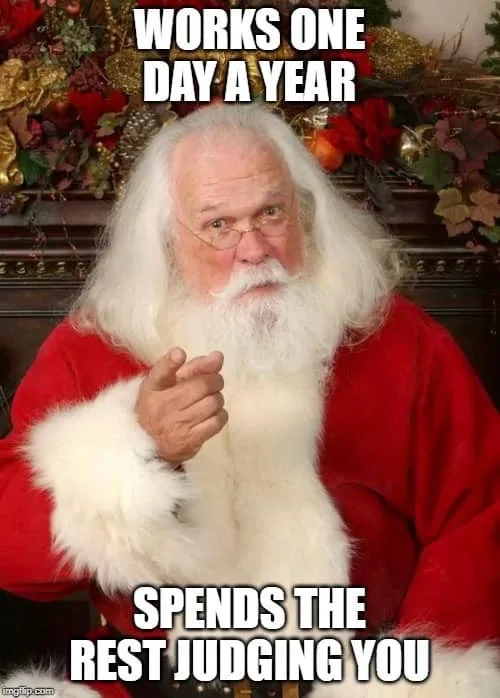 A man dressed as Santa Claus, wearing a red suit with white fur trim and glasses, points directly at the viewer. The image…