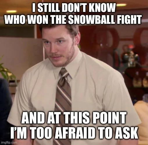 A man in a beige shirt and striped tie looks directly at the camera with a slightly confused and resigned expression. The…
