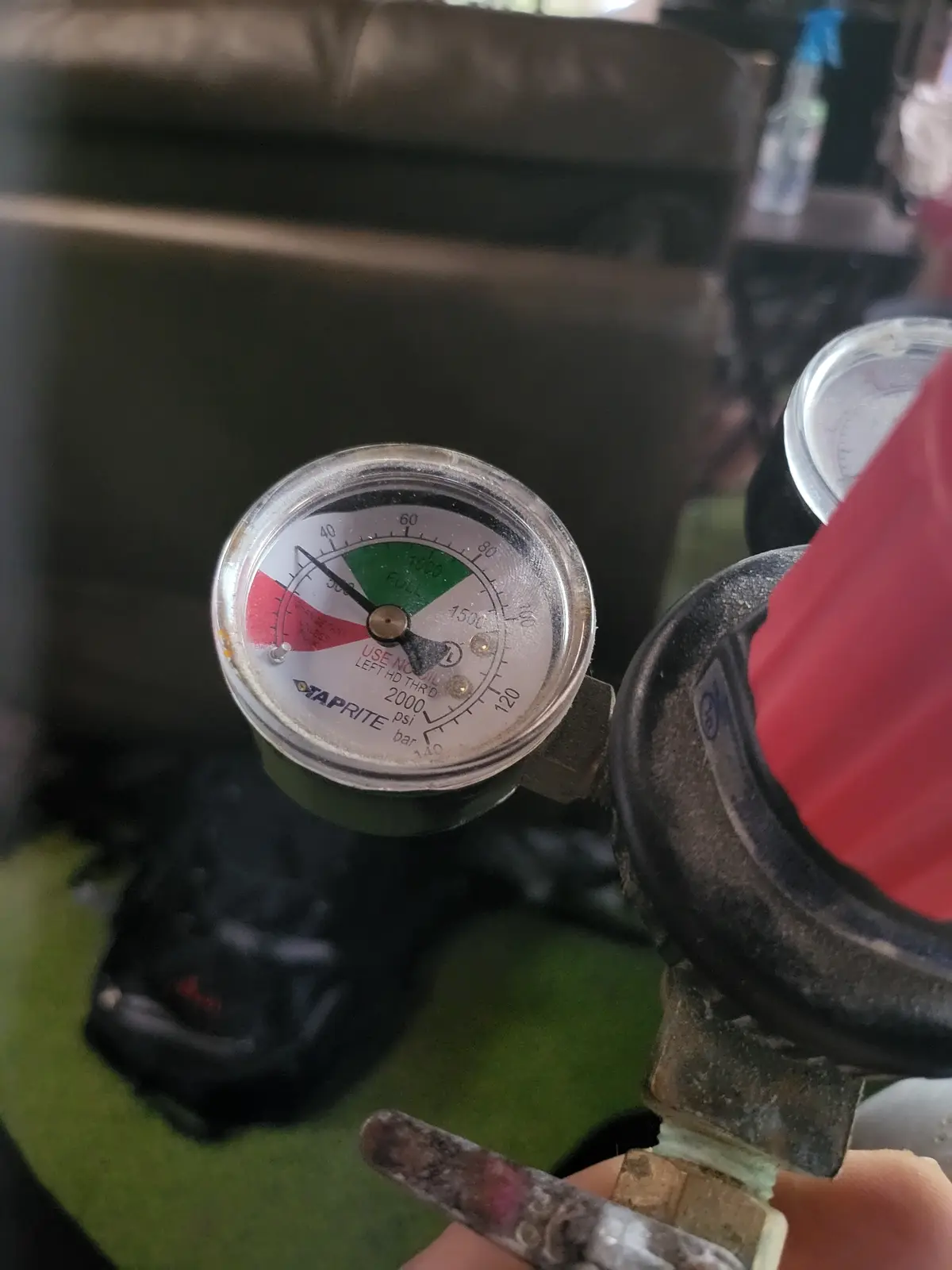 A close-up photo shows a hand turning a valve on an industrial pressure gauge, which reads 'USE NO OIL LEFT HD THRD 2000 psi…