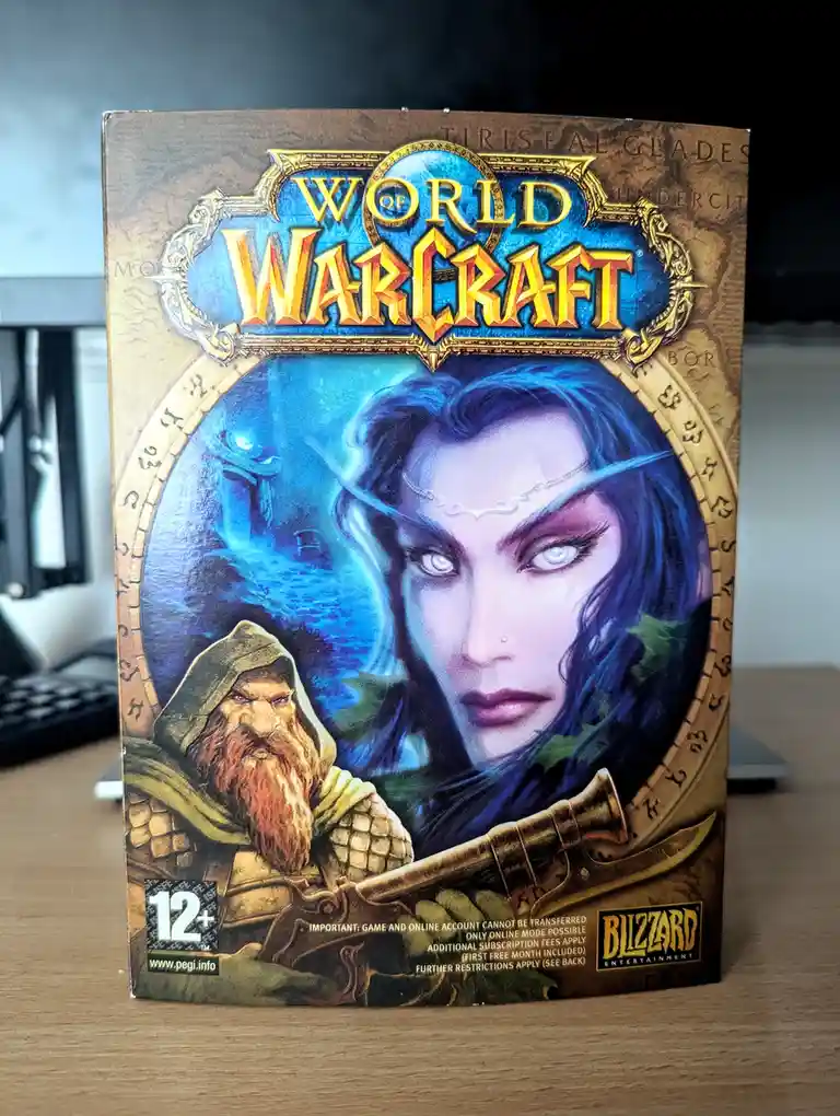 A physical copy of the World of Warcraft game box, featuring artwork of a blue-haired elf woman and a bearded dwarf warrior…