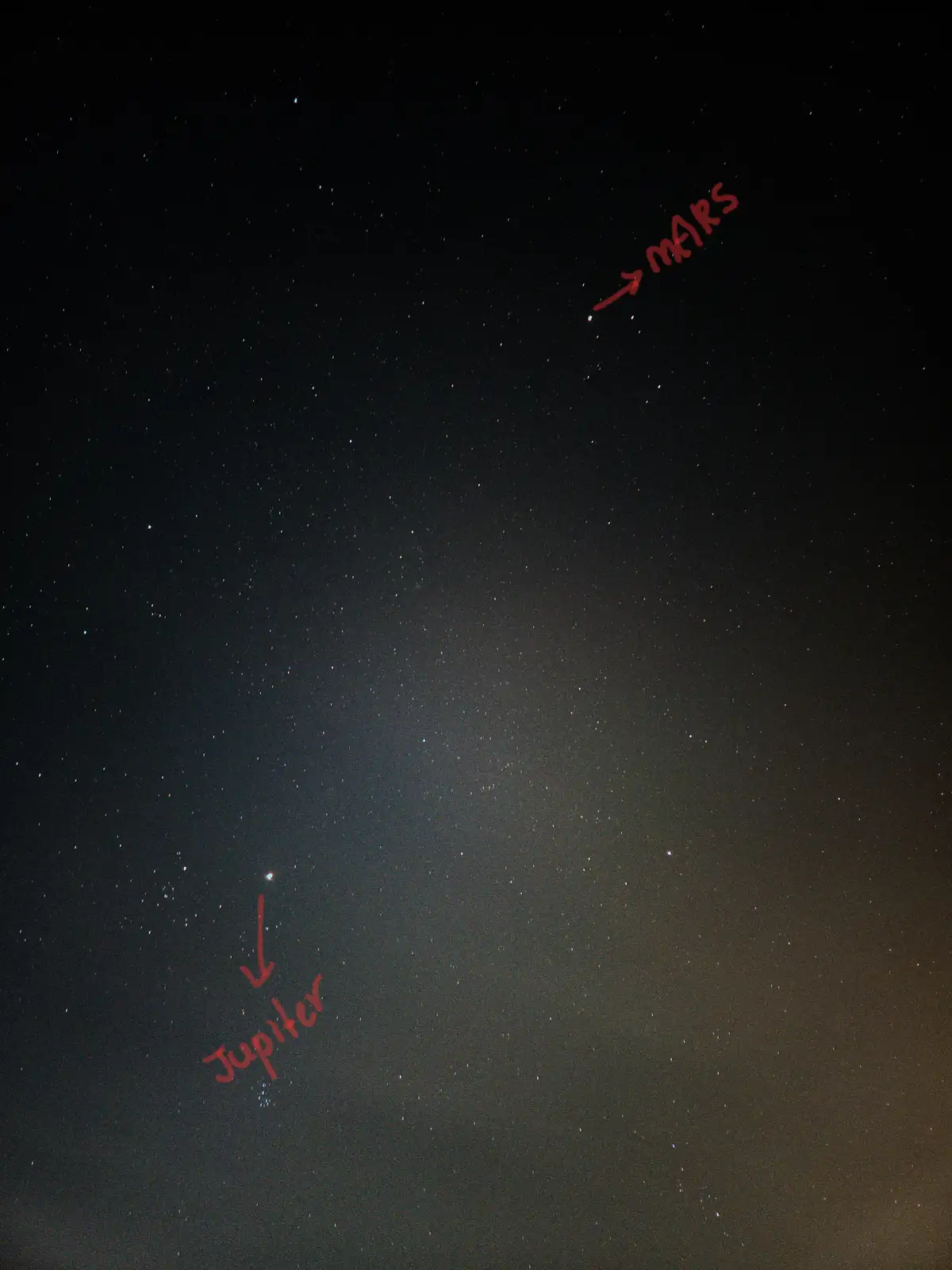 A night sky photo showing two bright celestial objects labeled with red handwritten text: one in the upper right labeled '→…