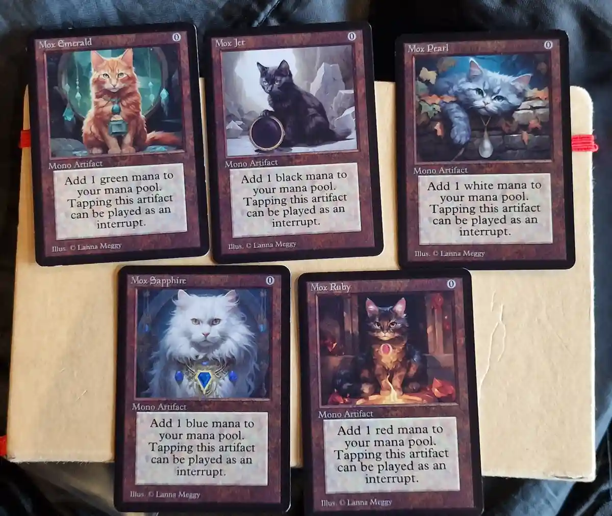 Five custom Magic: The Gathering cards are displayed, each featuring a different cat illustration and labeled as a 'Mox'…