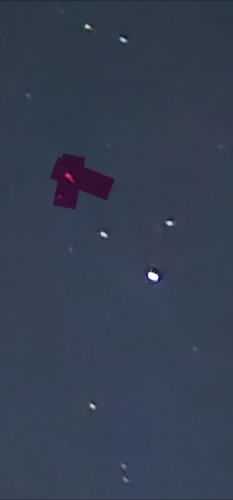 A dark sky with several bright points of light resembling stars. One of these lights is overlaid with a magenta crosshair…