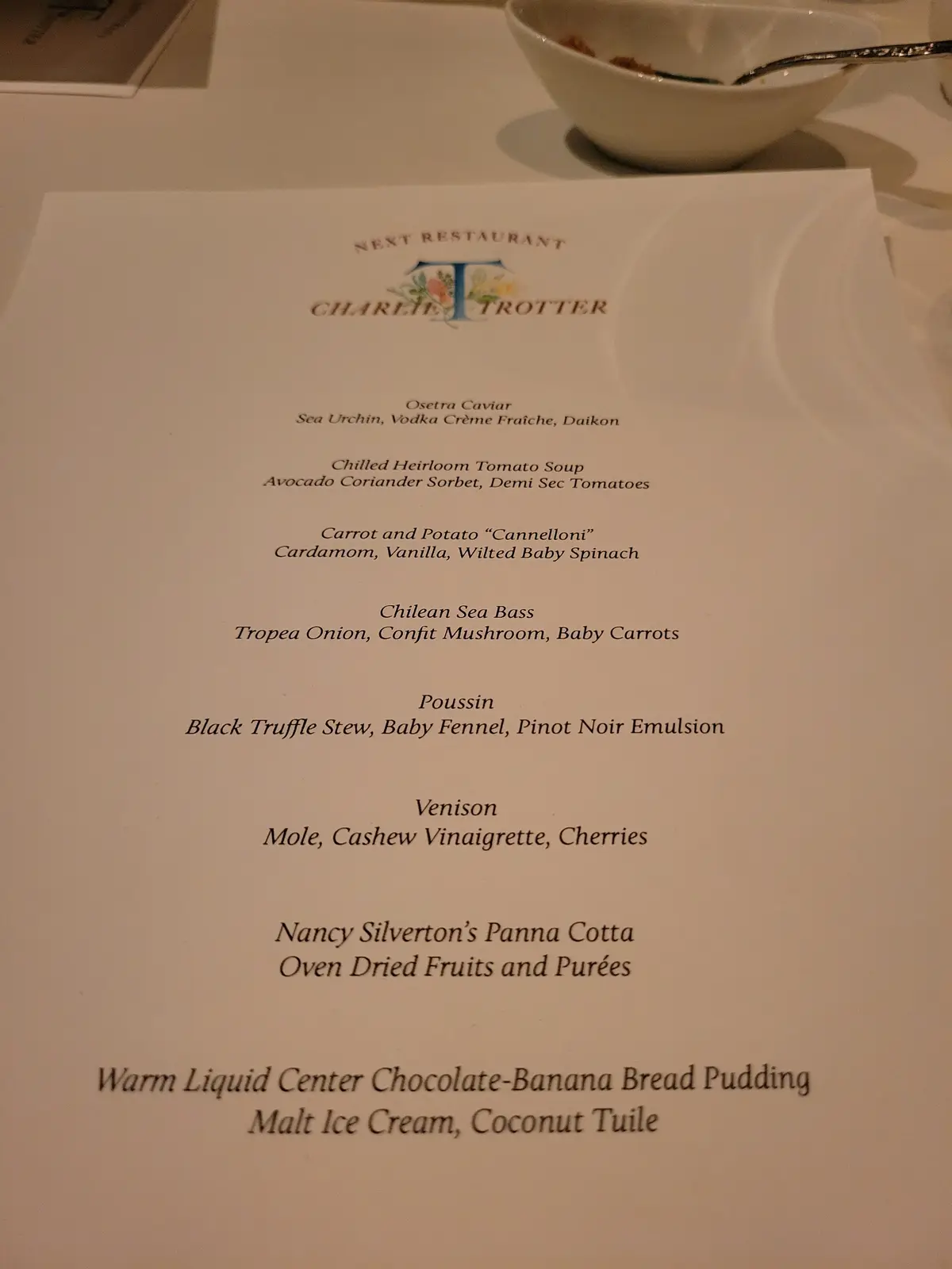 A close-up photo of a printed menu from Charlie Trotter's restaurant, listing dishes like Osetra Caviar, Chilean Sea Bass…
