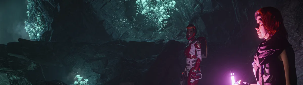 Two characters stand in a dark, rocky cave illuminated by glowing green fungi on the walls and ceiling. One character wears…