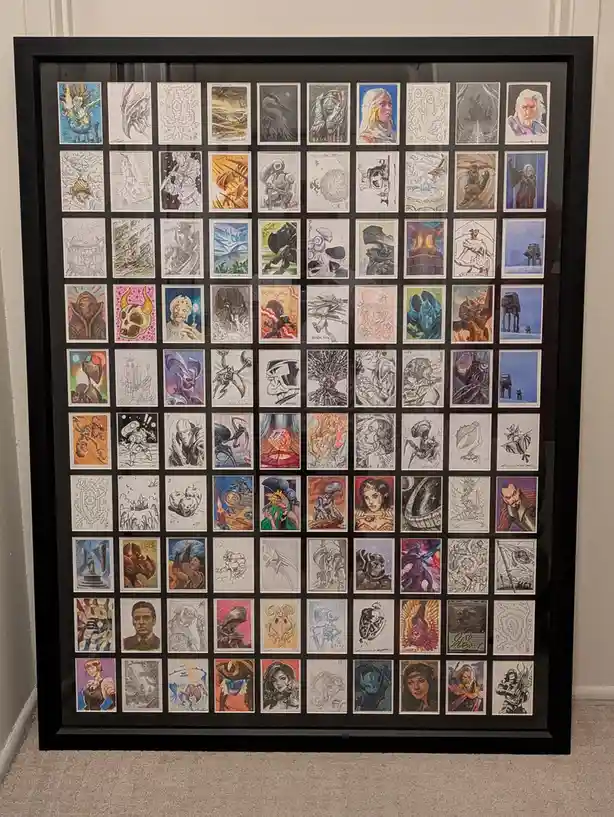 A large black-framed display case holds a grid of approximately 60 small, individually matted illustrations, showcasing…