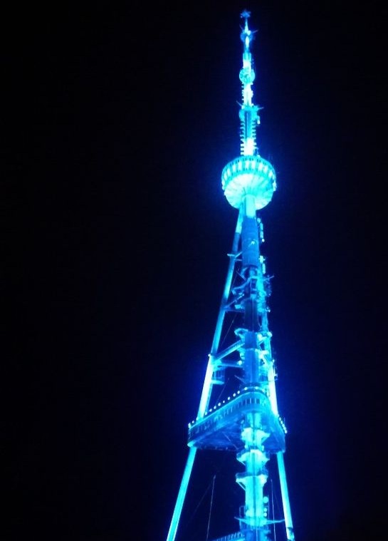A tall, illuminated broadcast tower lit in blue against a dark night sky, with the overlaid text 'i'm not crying, you're…