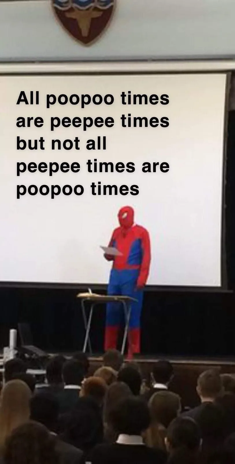 A person in a full Spider-Man costume stands at a lectern in front of an audience, delivering a presentation. Behind them is…