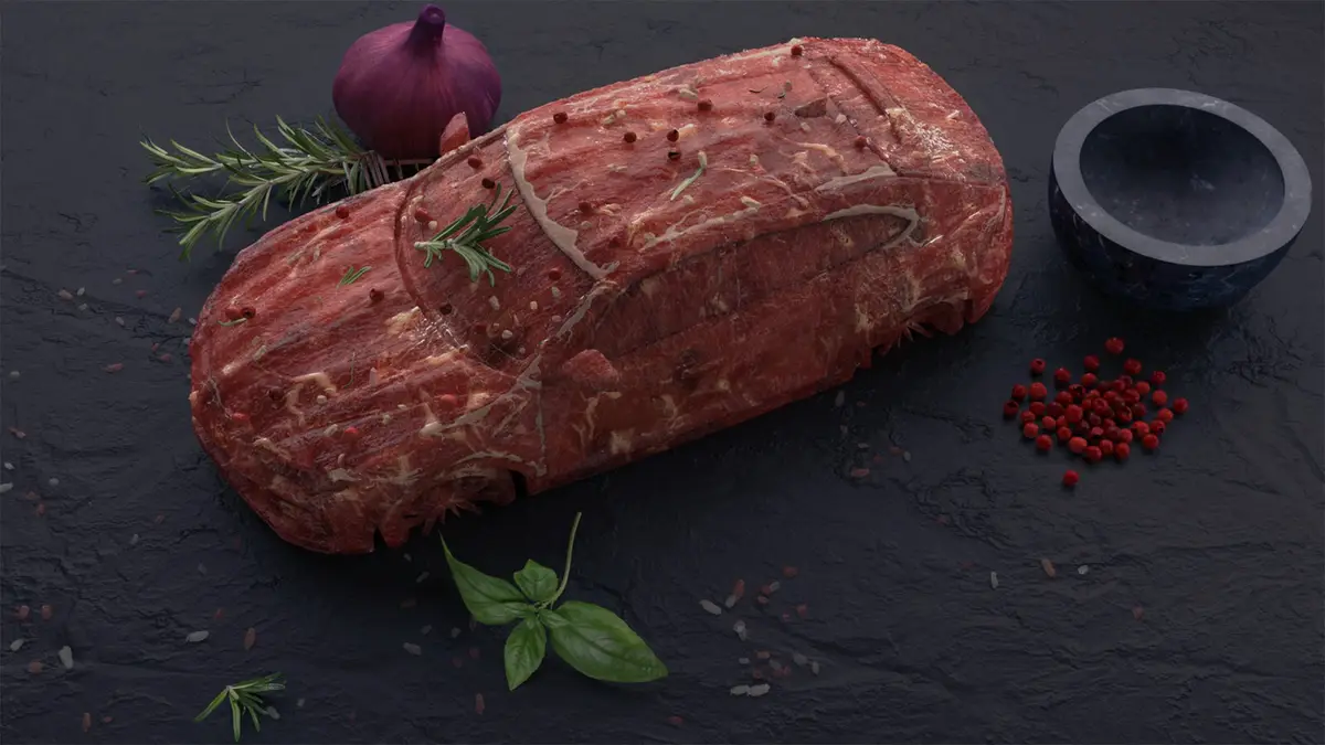 A raw, seasoned meat roast is meticulously sculpted to resemble a car, complete with visible details like windows and doors…
