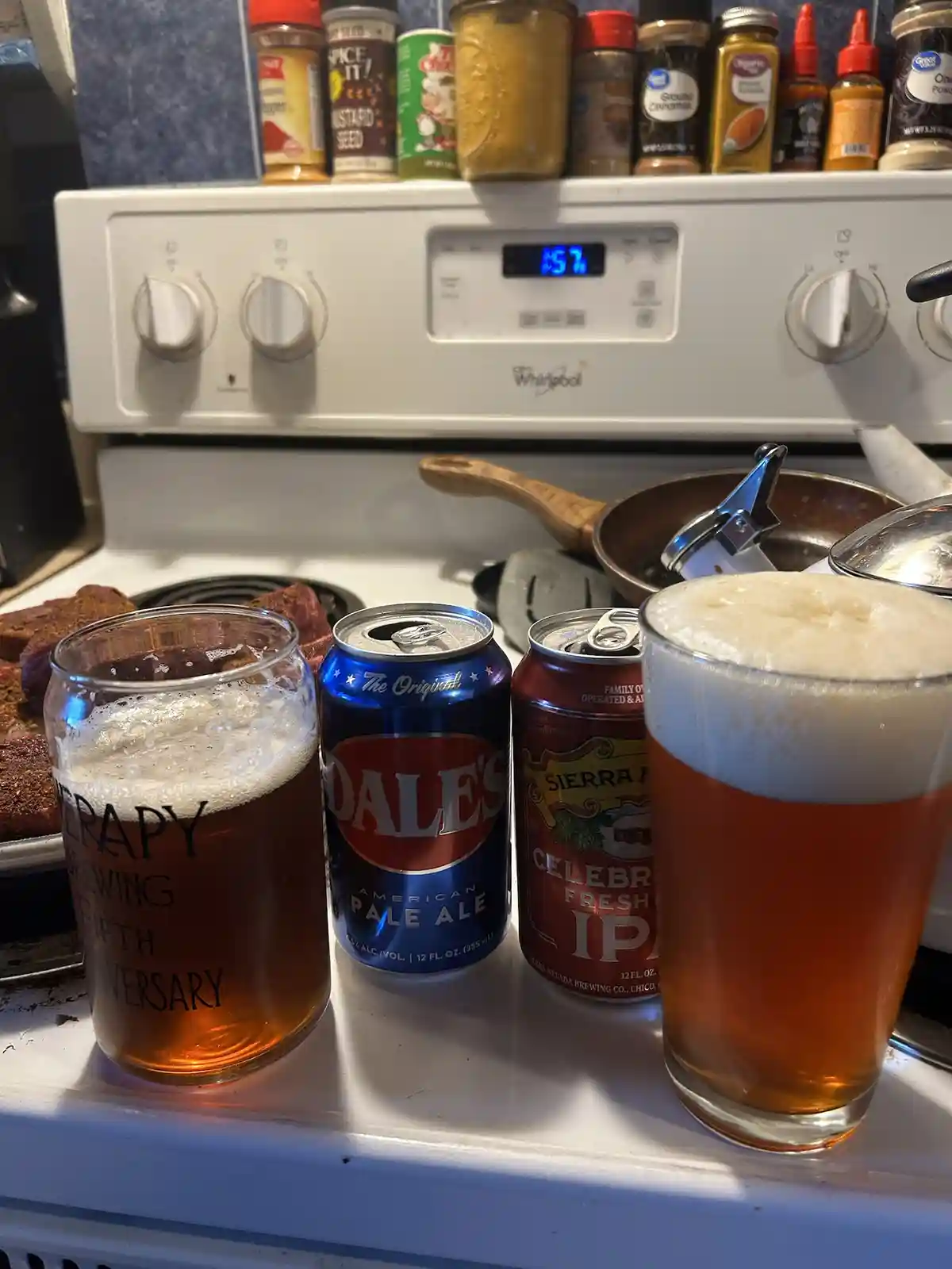 A photo of a kitchen stove with two glasses and two beer cans on the stovetop. One glass has "therapy brewing fifth…