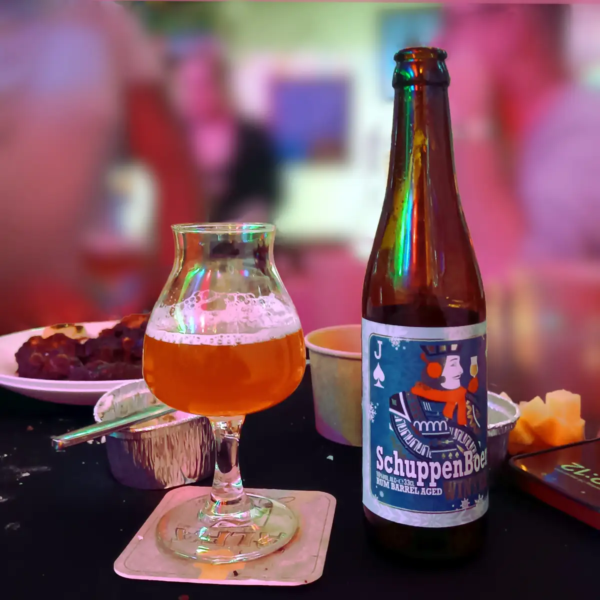 A close-up photo shows a brown bottle of SchuppenBoer Winter beer next to a tulip-shaped glass filled with amber beer and…