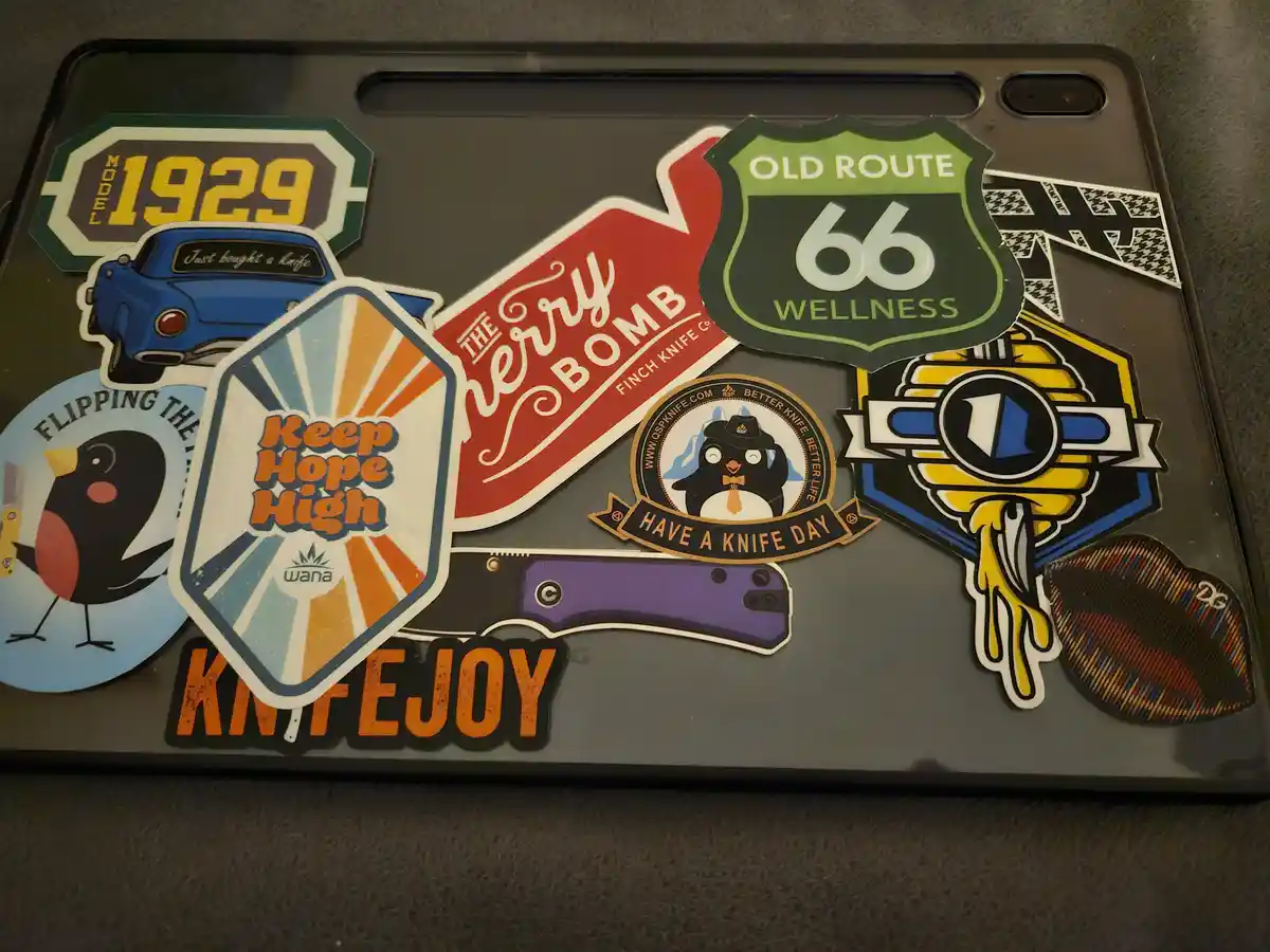 A black tablet case is covered in colorful stickers, including 'Keep Hope High', 'Old Route 66 Wellness', 'The Cherry Bomb'…