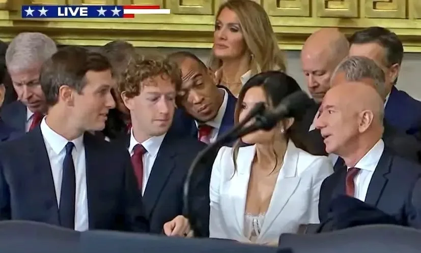 A group of people, including Jeff Bezos and Mark Zuckerberg, are seated at a formal event with a 'LIVE' broadcast banner…
