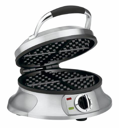 A silver, open waffle maker with black non-stick grids is shown against a white background. The appliance has a handle on…