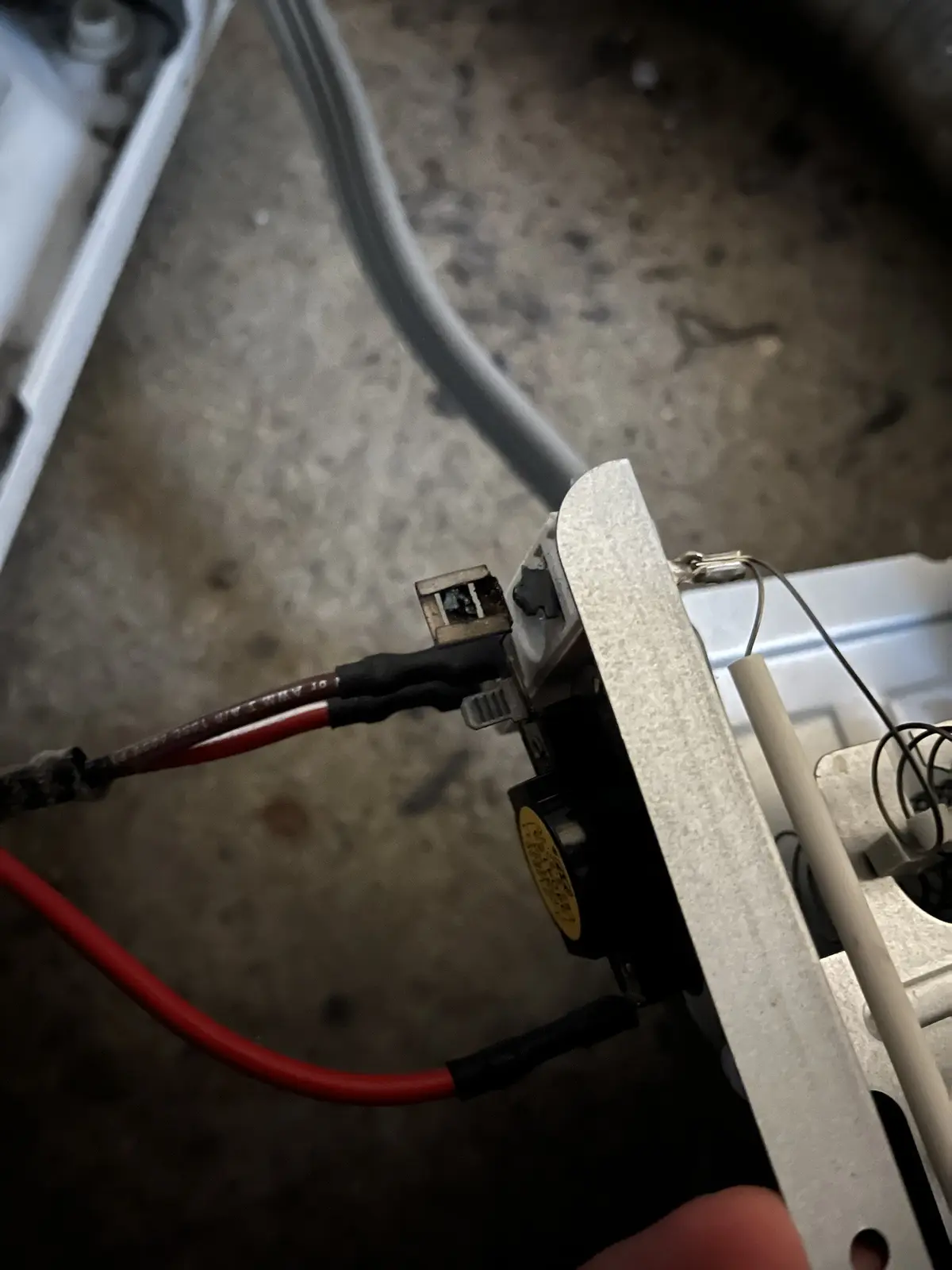 A close-up photo shows a damaged electrical connector with melted plastic and burnt wires, attached to a metal appliance…