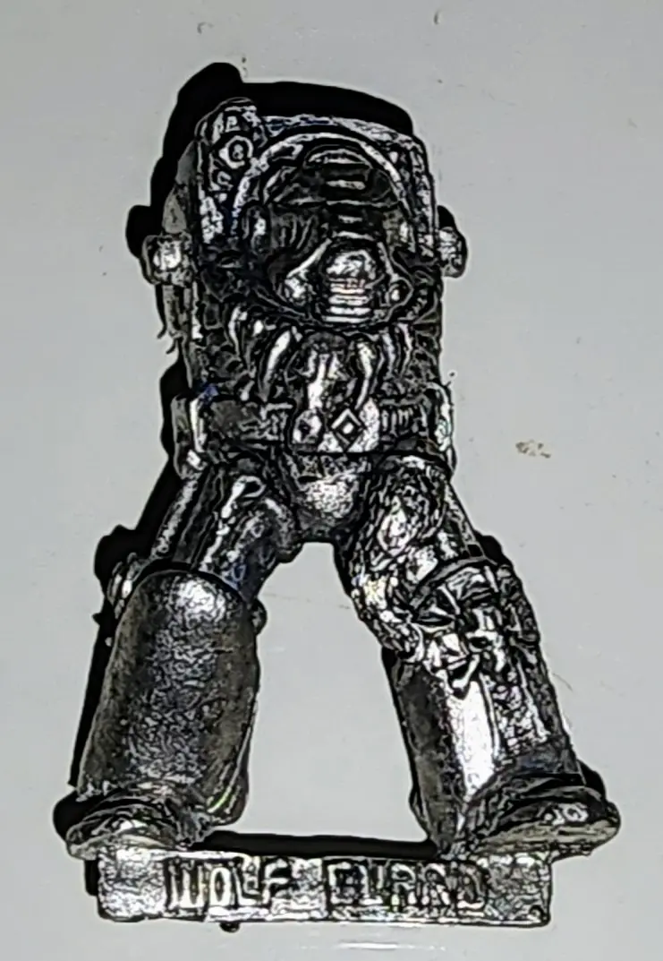 A silver-colored miniature figurine of a heavily armored, grim-faced warrior stands on a base with the text 'WOLF BLIND'…