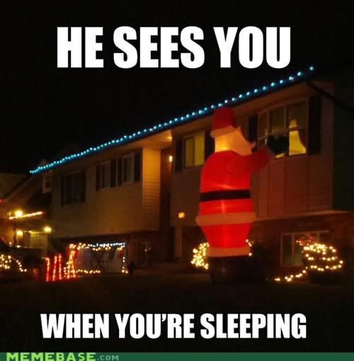 A nighttime photo of a house decorated with Christmas lights, featuring a large inflatable Santa Claus figure standing in…