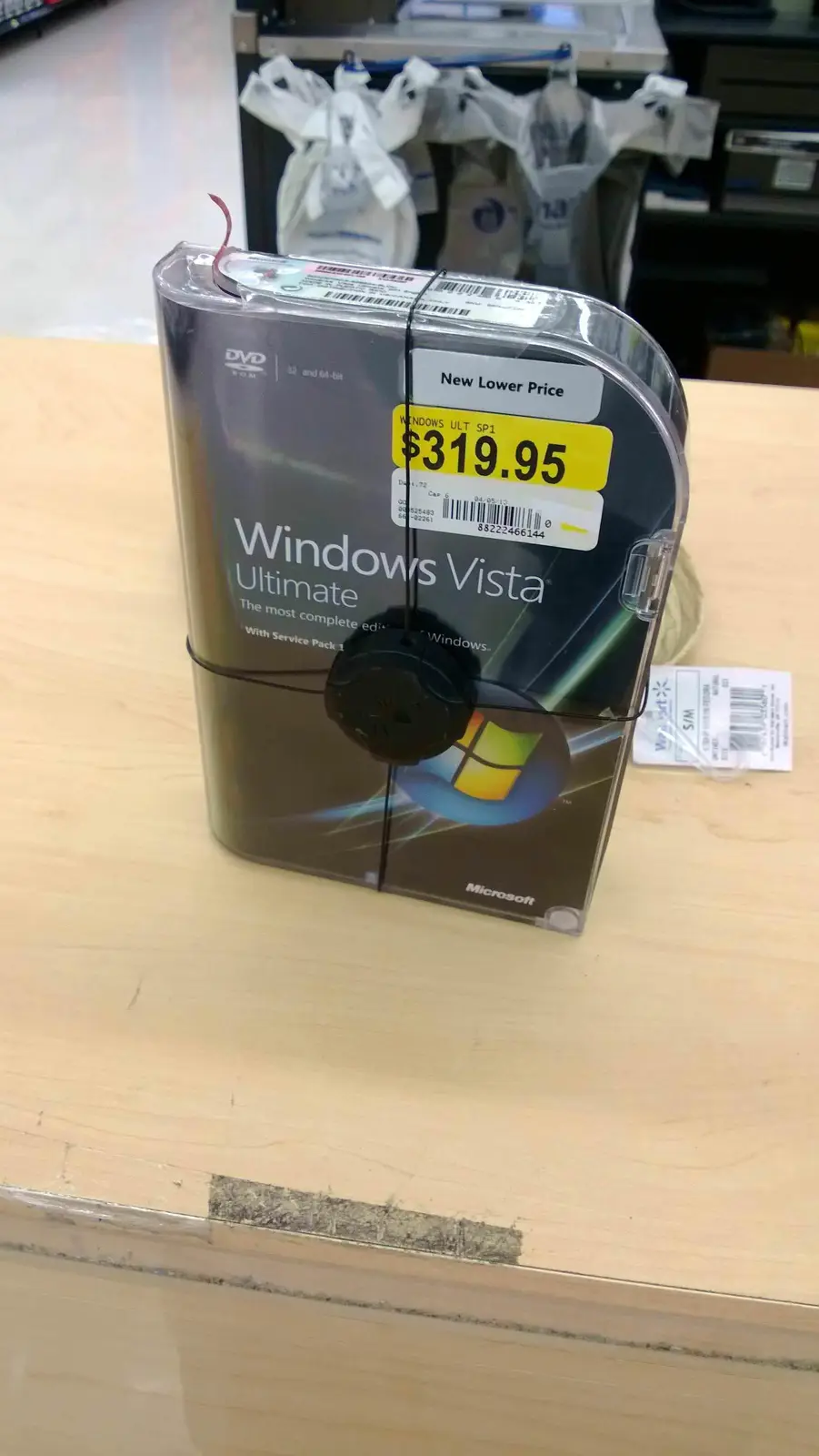 A Windows Vista Ultimate software box, visibly priced at $319.95 with a 'New Lower Price' tag, is displayed on a store…
