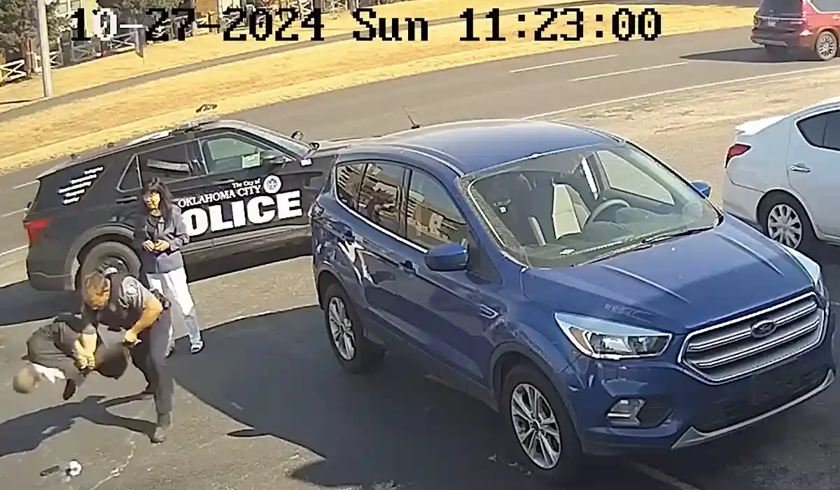 A security camera timestamped October 27, 2024, shows an Oklahoma City Police officer arresting a man on the pavement next…