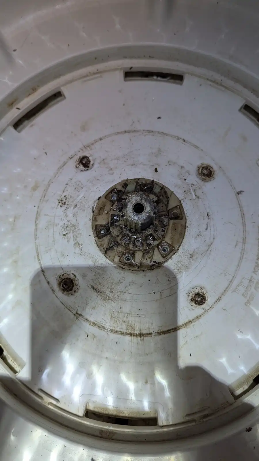 A close-up photo shows the dirty, grimy bottom of a white blender base, with a central gear mechanism caked in brown residue…
