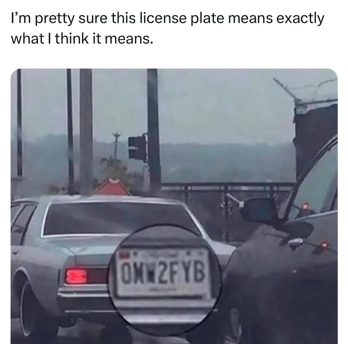 A silver car is stopped at an intersection with a license plate reading '0MW2FYB' highlighted by a circular magnifying glass…