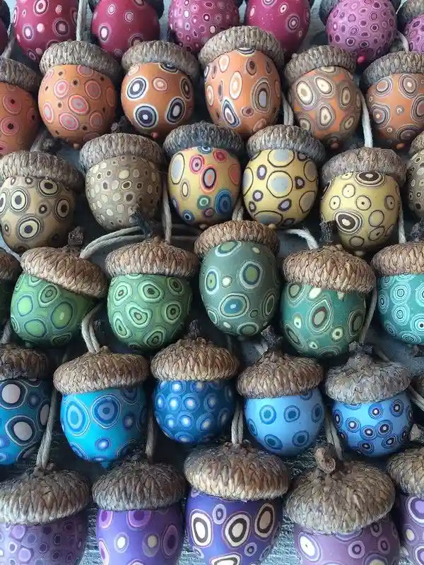 a dense arrangement of hand-painted acorns, each decorated with colorful concentric circles in various hues like orange…