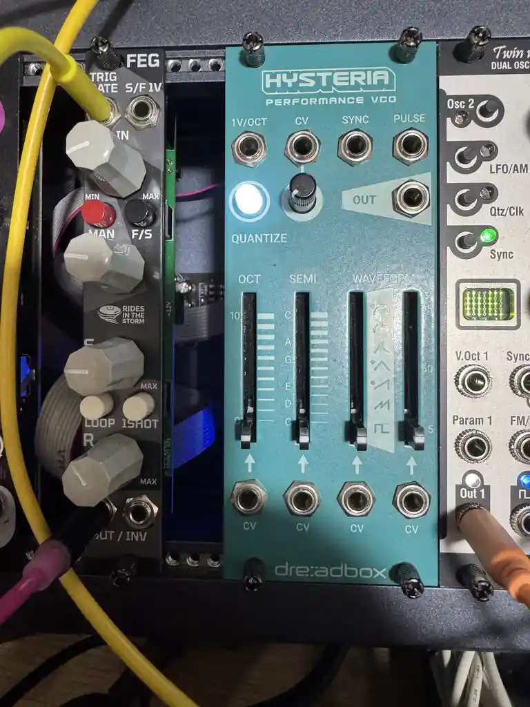 A close-up photo of a teal 'Hysteria Performance VCO' analog synthesizer module by dre:adbox, showing its knobs, sliders…