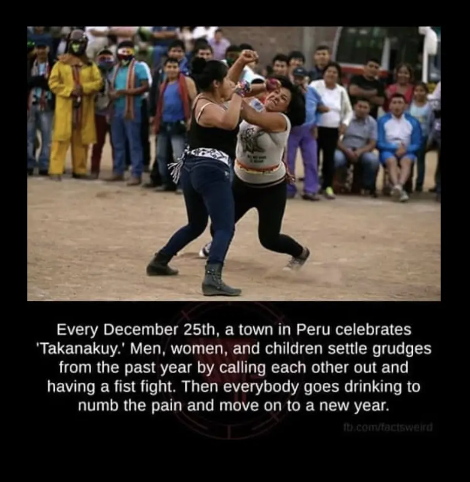 Two women are engaged in a physical fistfight in an outdoor dirt area, surrounded by a crowd of onlookers. The overlaid text…