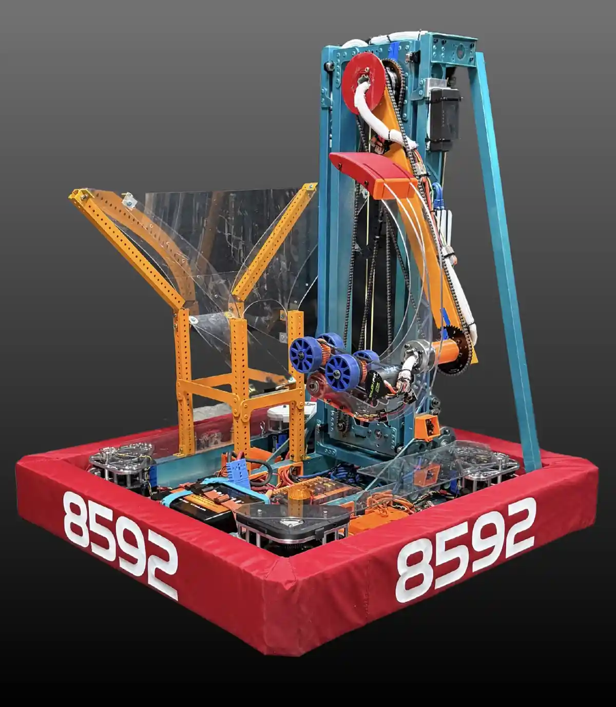 A complex, custom-built robot with a red padded base displaying the number 8592 on both sides, featuring a tall blue frame…