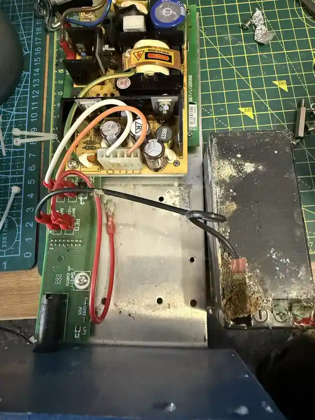 A close-up photo shows the inside of a broken electronic device, likely a power supply, with exposed circuit boards, wires…