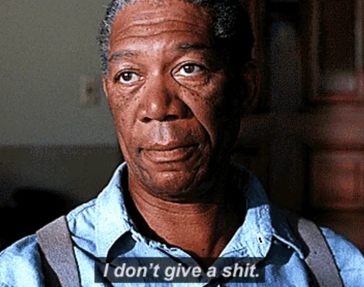 A close-up of actor Morgan Freeman looking directly at the camera with a calm, unbothered expression. He wears a blue…