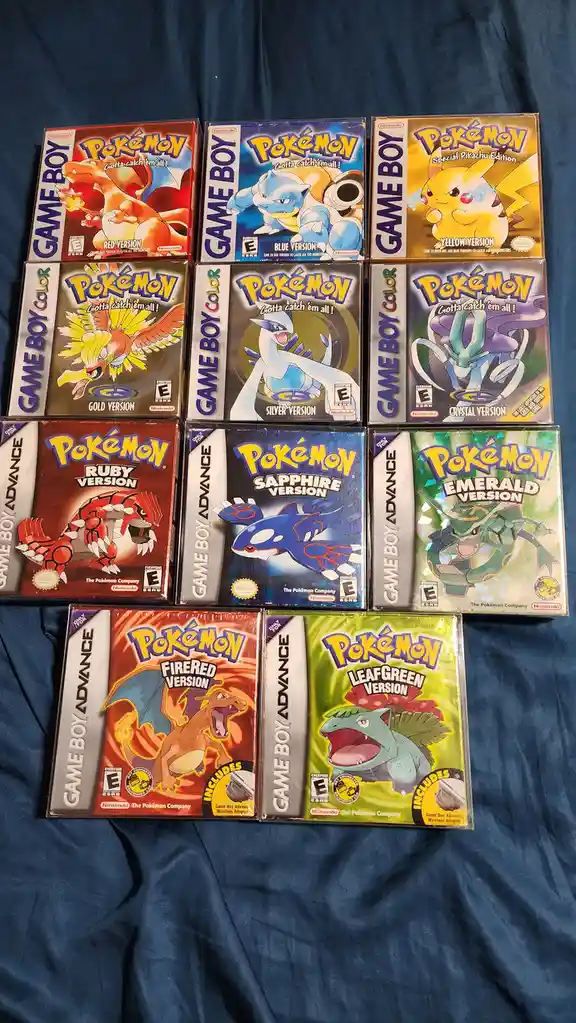A collection of ten Pokémon video game cartridges for Game Boy and Game Boy Advance systems, arranged in a grid on a blue…