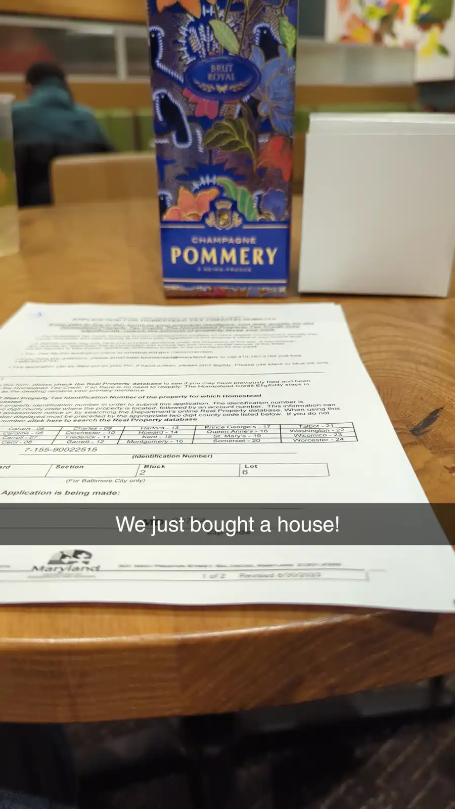 A close-up photo shows a Maryland Homestead Tax Credit Eligibility application form on a wooden table, with a decorative…