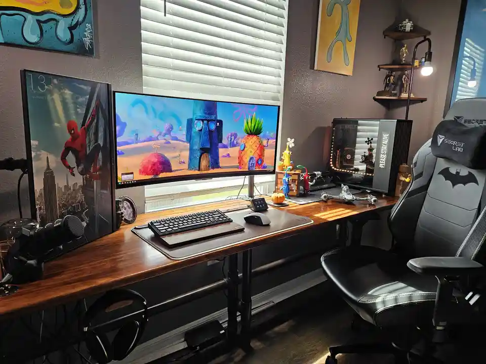 A well-lit gaming setup features a large monitor displaying a SpongeBob SquarePants scene, a second monitor showing…