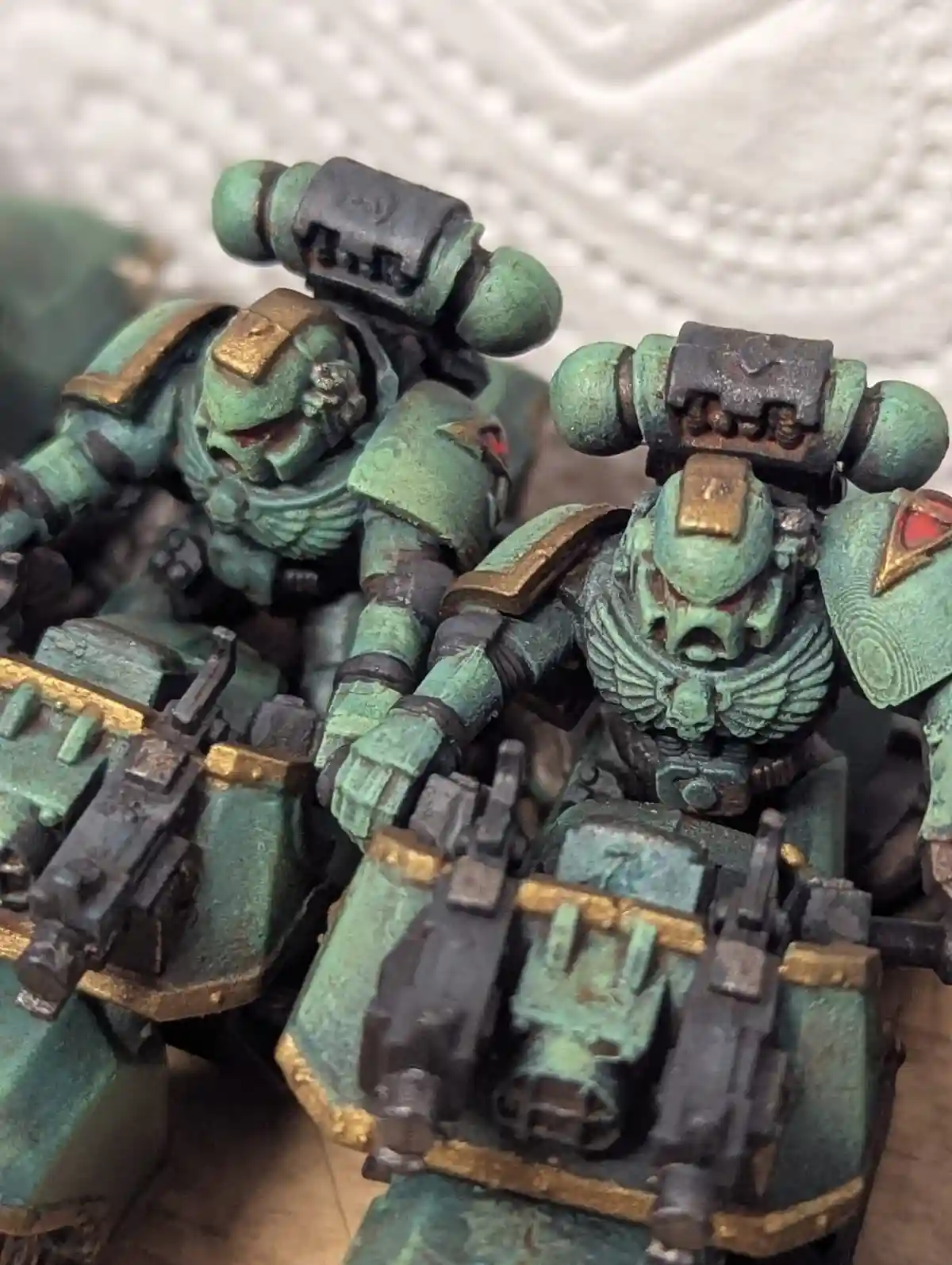 A close-up photo shows two heavily weathered, green-painted miniature space marines with rust and chipping paint, looking…