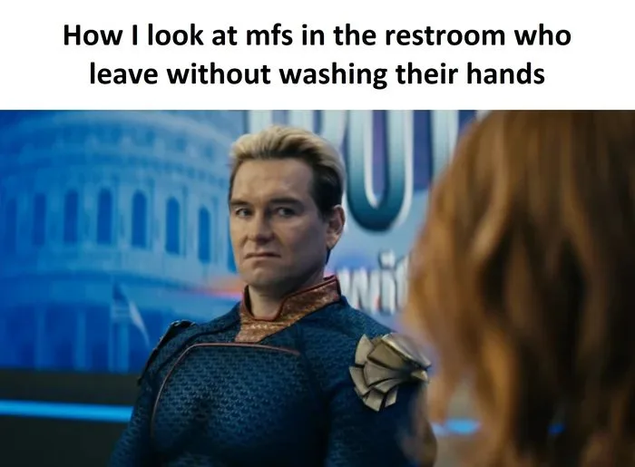 A man in a blue superhero costume with a stern, judgmental expression looks at someone with red hair whose back is to the…
