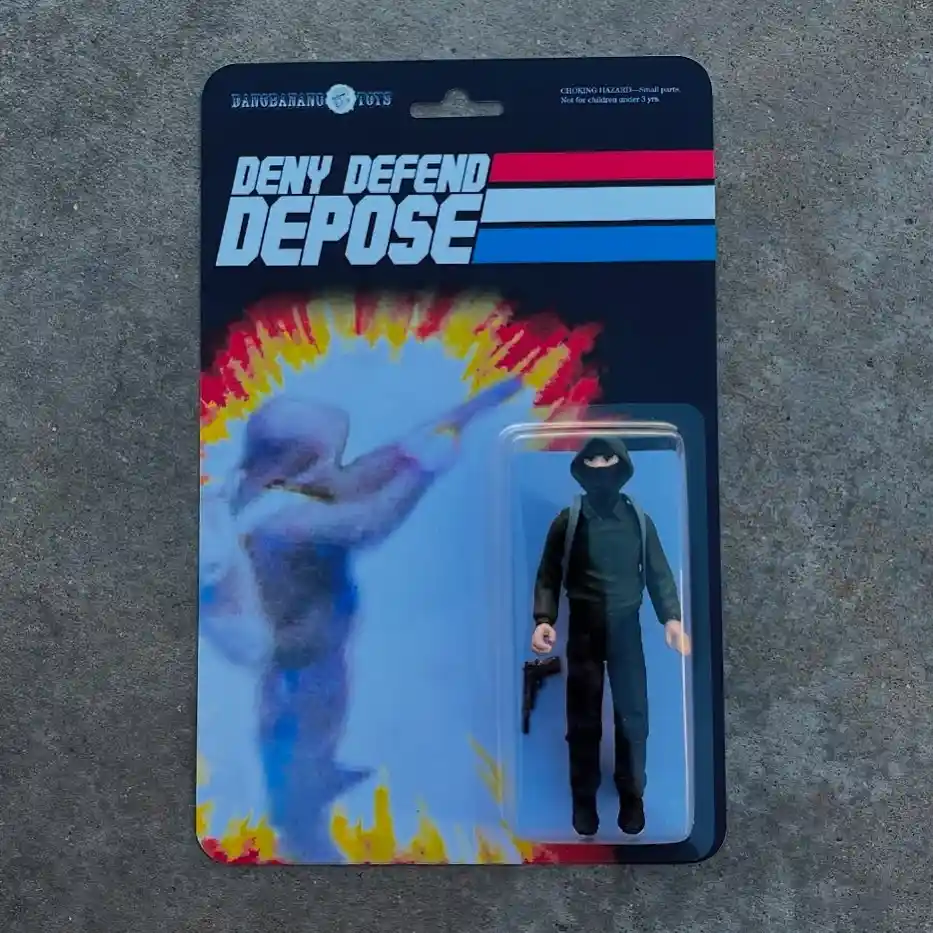 A toy action figure in a clear plastic blister pack on a cardboard backing, featuring a figure in a black hoodie and pants…