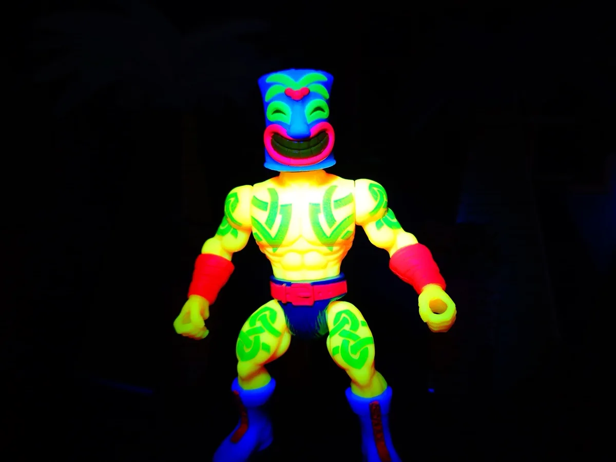 A brightly colored, fluorescent wrestling action figure with a tiki mask head, glowing green tribal patterns on its yellow…
