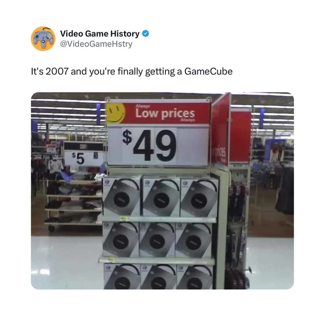 A retail store shelf displays multiple GameCube consoles in their original packaging, priced at $49 under a 'Low prices'…