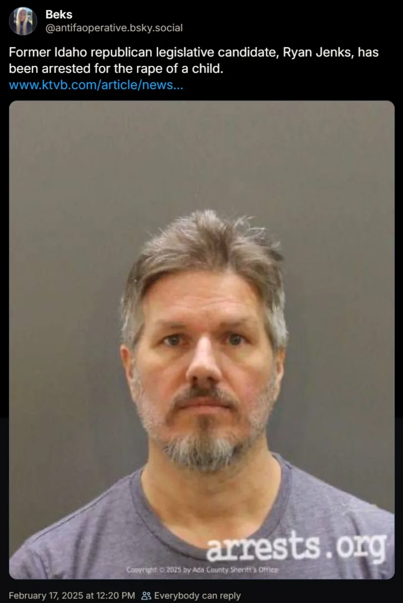 A mugshot of a middle-aged man with graying hair and a goatee, wearing a gray t-shirt, against a plain gray background. The…