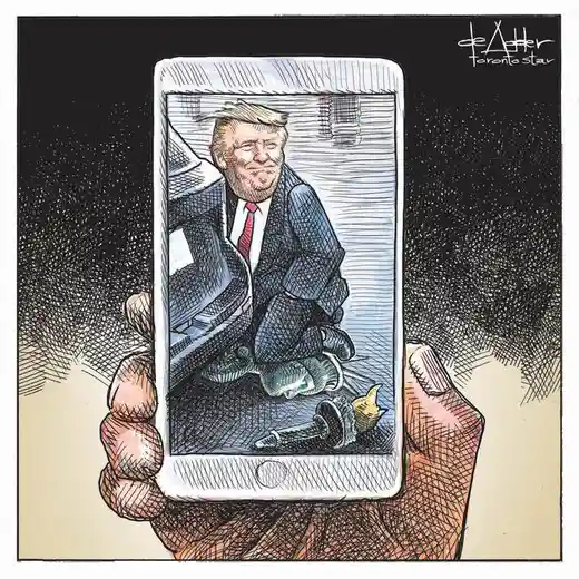 A hand holds a smartphone displaying a cartoon of Donald Trump sitting on the ground with a broken phone and a broken pen…